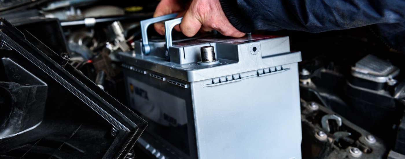 Mechanic putting a new battery into a vehicle