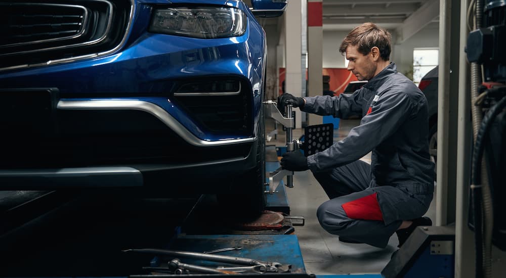 Mechanic performing a wheel alignment on a blue car