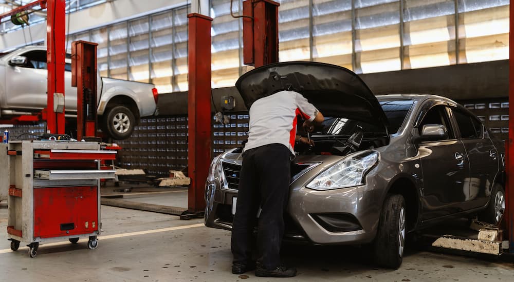 Mechanic working on the engine of a silver Nissan getting auto repair near Cypress