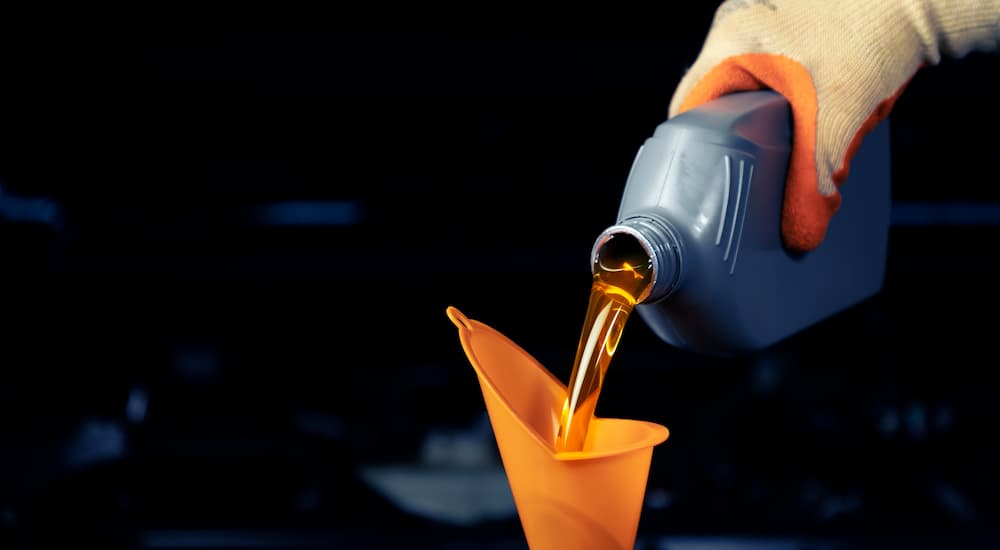 Oil being poured out of a bottle into a car engine at a lube center