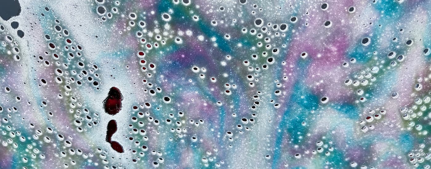 Rainbow soap bubbles on a windshield during a car wash