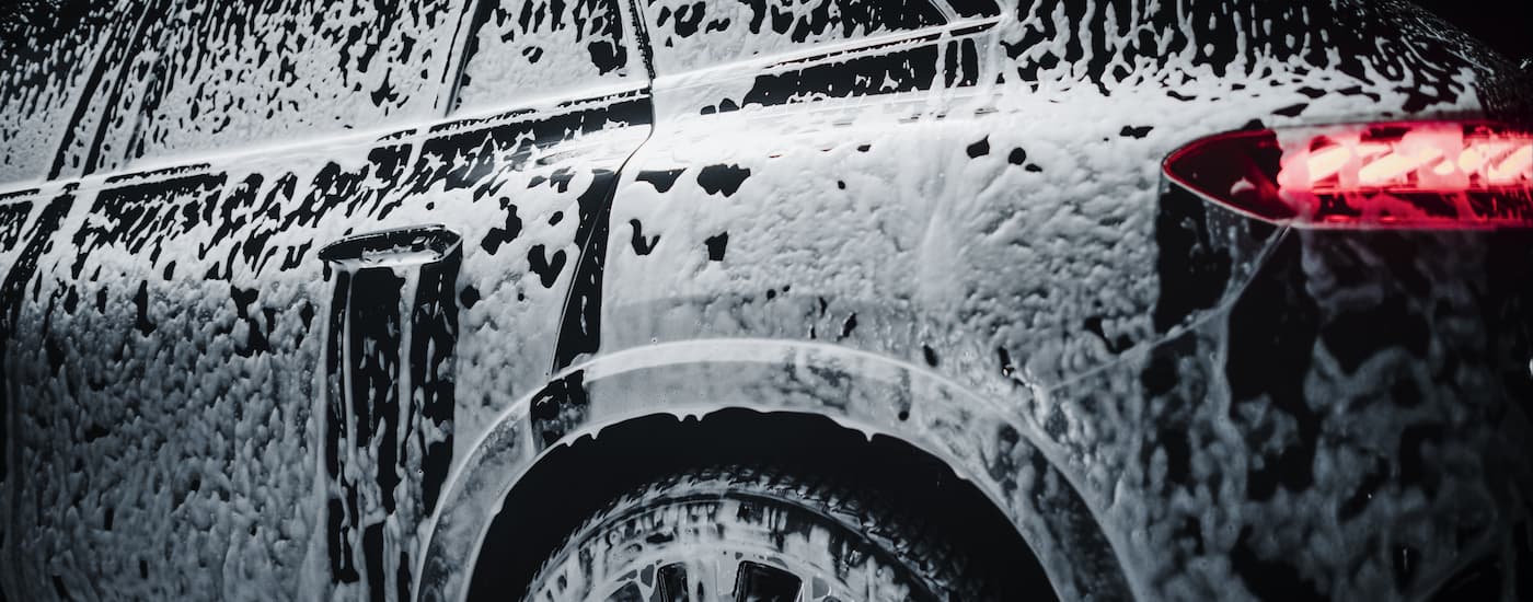 Black SUV covered in soap suds at a car wash